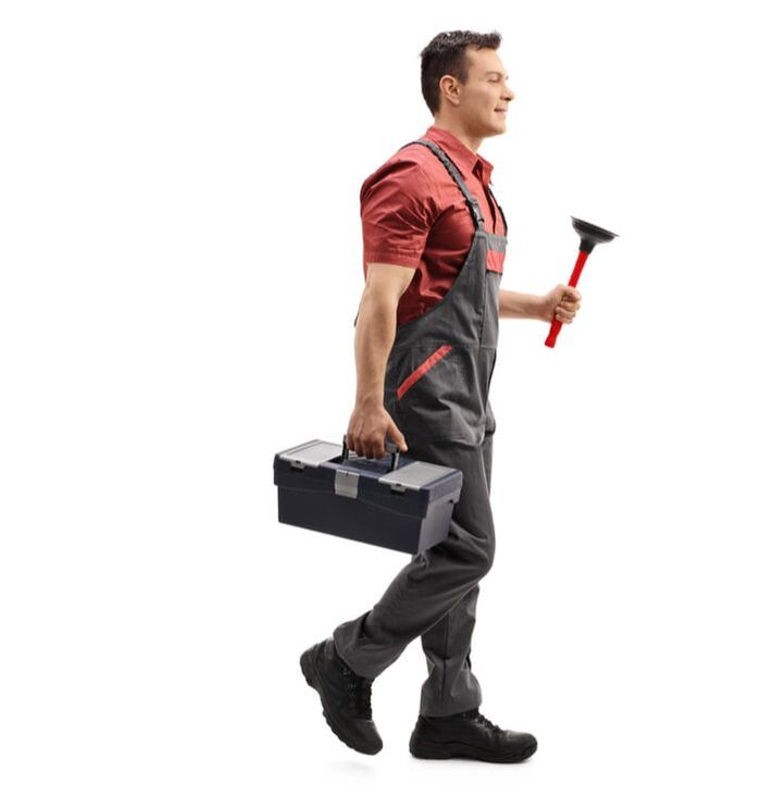 Plumbing in red shirt and gray overalls holding plunger and tool box while walking